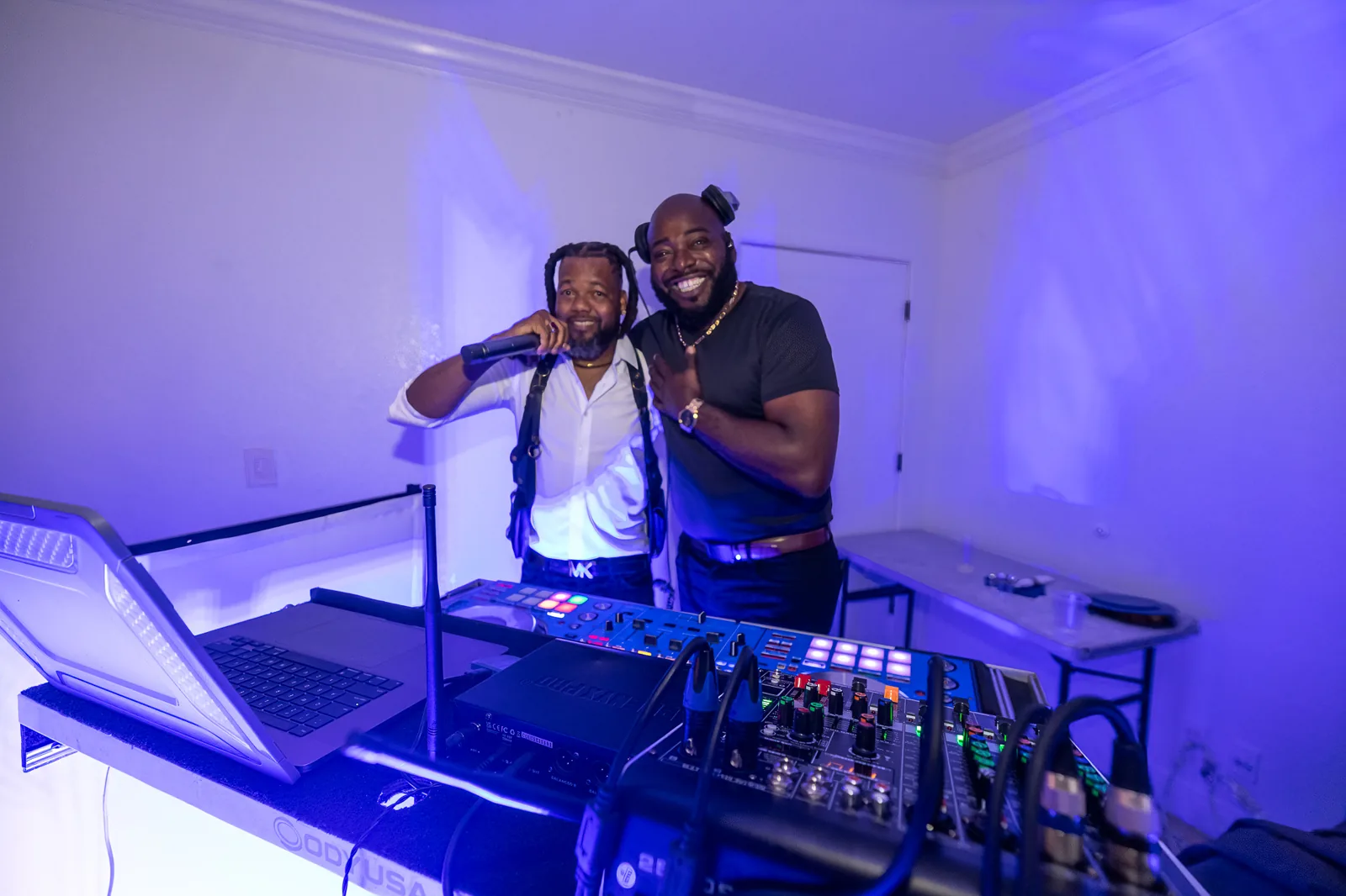 DJ and guest smiling beside the music setup