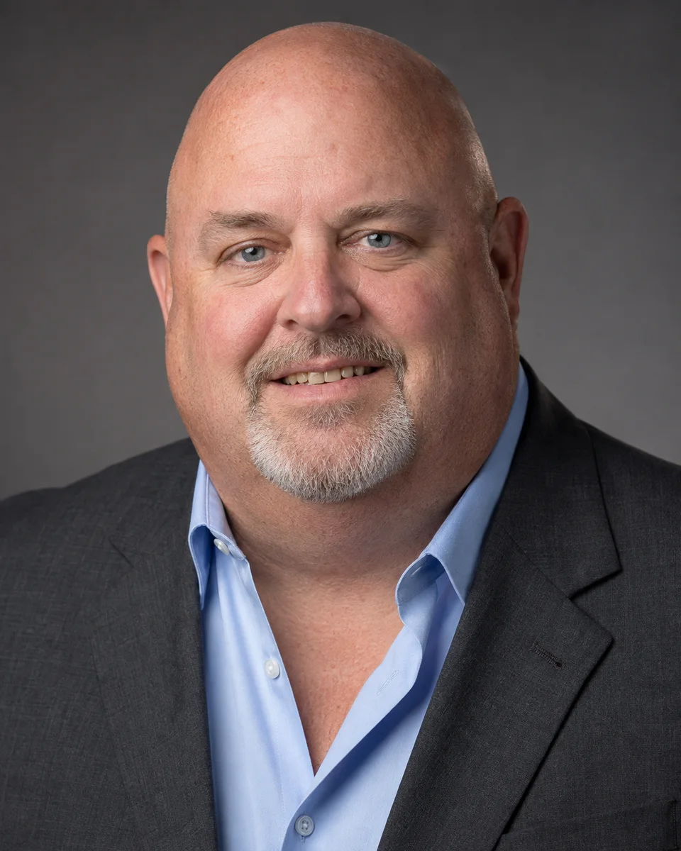 Headshot in a dark jacket and blue shirt